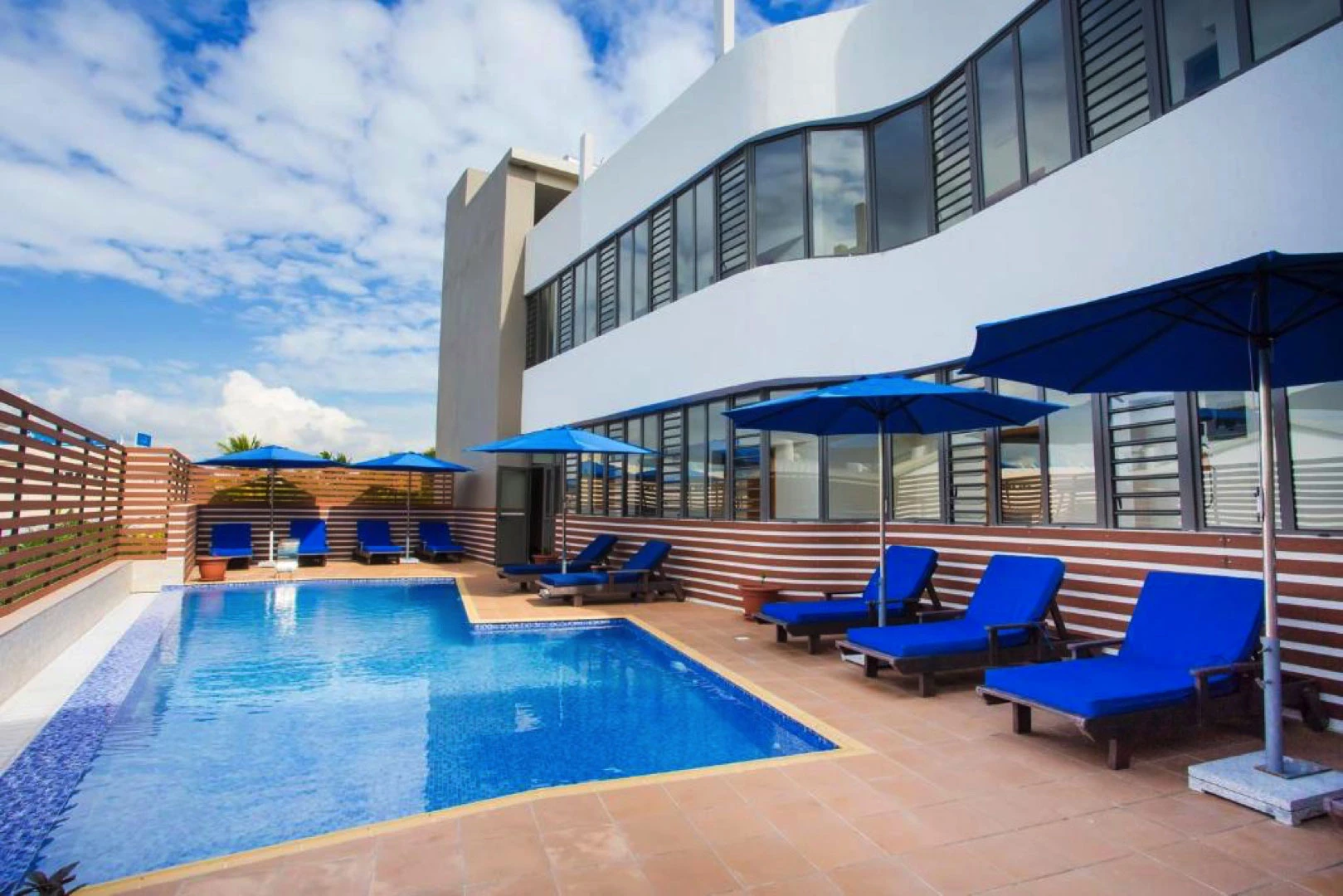 Residence Potosi residential pool with sun loungers and blue umbrellas.