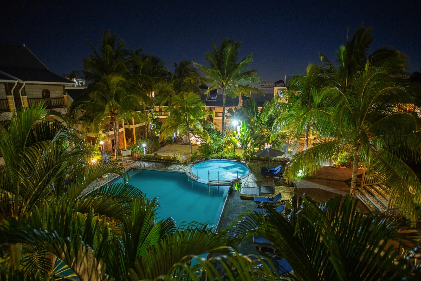 Le Palmiste Resort & Spa pool at night with garden lighting.