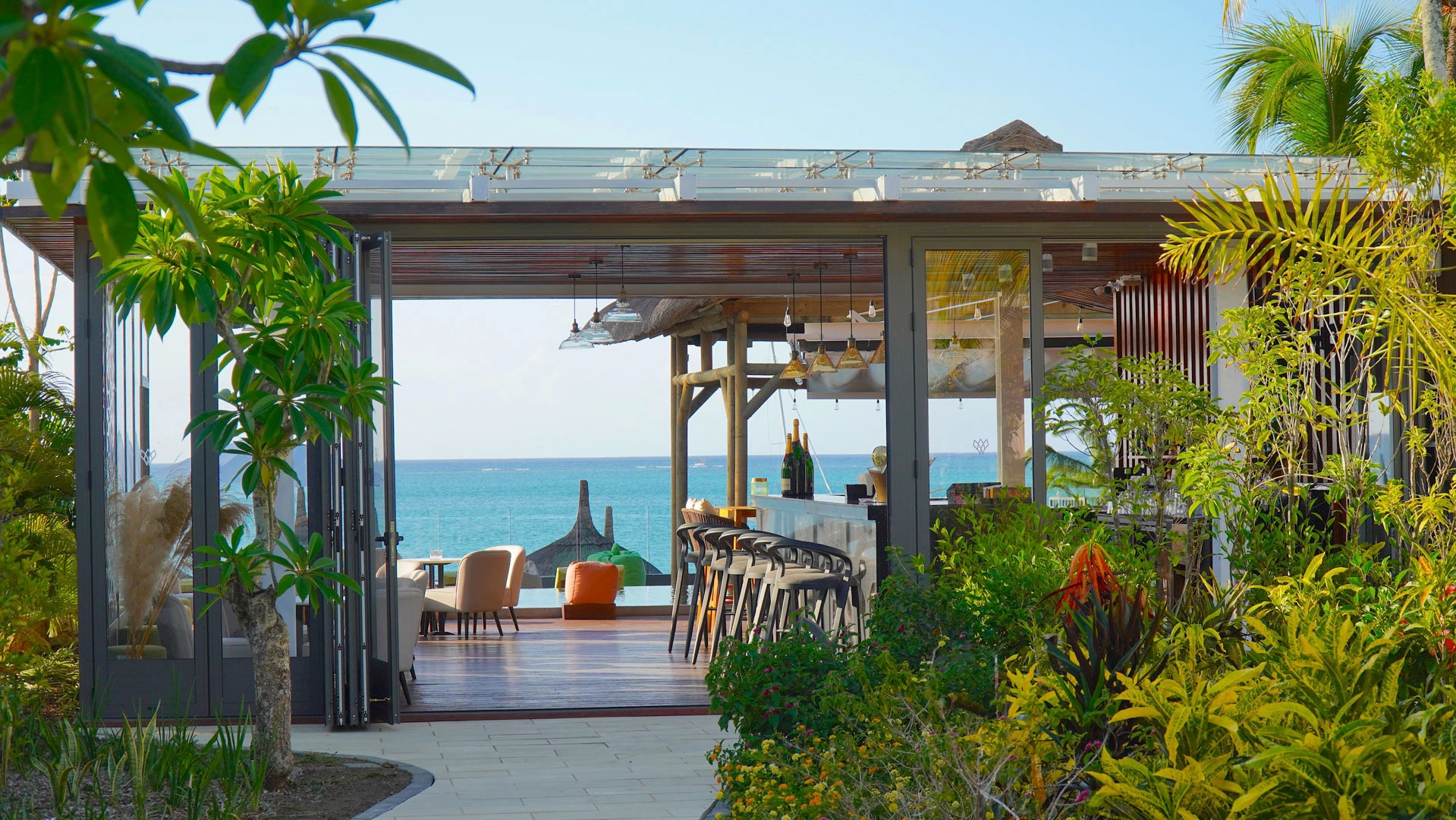 Elegant entrance of the Wonders Beach hotel bar with ocean view and lush tropical vegetation
